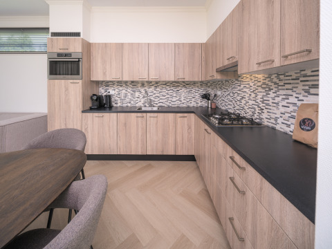 Cucina moderna al Batenburgh Deluxe lodge a Veluwepark de Bosgraaf, Paesi Bassi, con mobili in legno e piano nero.