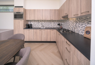 Cucina moderna al Batenburgh Deluxe lodge a Veluwepark de Bosgraaf, Paesi Bassi, con mobili in legno e piano nero.