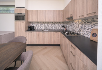 Cuisine moderne du lodge Batenburgh Deluxe à Veluwepark de Bosgraaf, Pays-Bas, avec placards en bois clair.