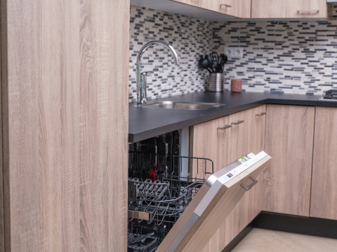 Cucina moderna con lavastoviglie aperta, mobili in legno e piastrelle presso Batenburgh Deluxe a Veluwepark de Bosgraaf.