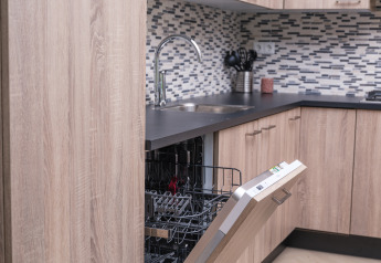 Cuisine moderne avec lave-vaisselle ouvert, armoires en bois et crédence, au Batenburgh Deluxe, Veluwepark de Bosgraaf.