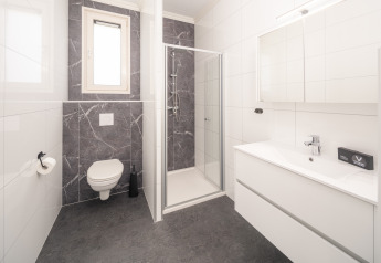 Modern bathroom at Batenburgh Deluxe, Veluwepark de Bosgraaf, Netherlands, with shower, toilet and sink.