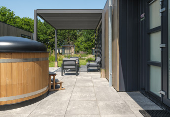 Außenterrasse der Batenburgh Deluxe Lodge im Veluwepark de Bosgraaf mit Whirlpool und Sitzmöbeln.