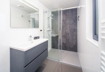 Modernes Badezimmer mit Dusche, großem Spiegel und Waschbecken in einer Lodge im Veluwepark de Bosgraaf, Niederlande.