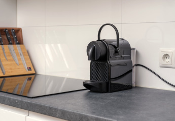 Pequeña cocina glamping con cafetera Nespresso, juego de cuchillos y encimera moderna de piedra.