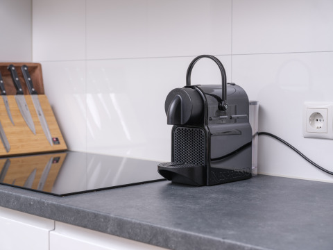 Pequeña cocina glamping con cafetera Nespresso, juego de cuchillos y encimera moderna de piedra.