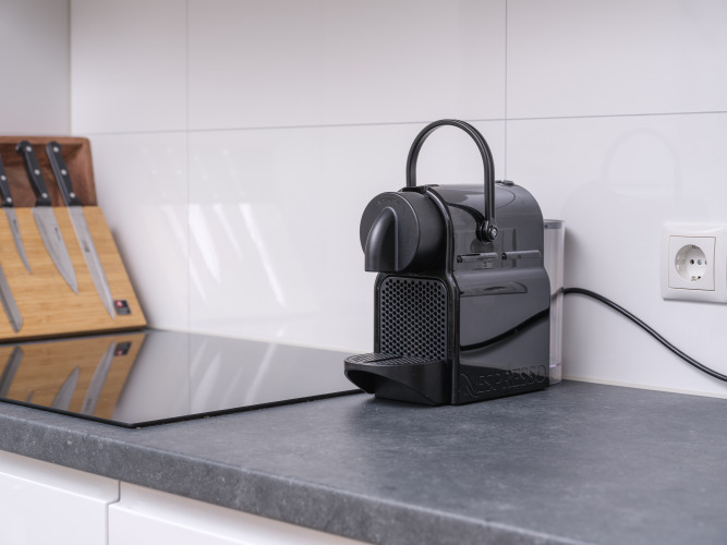 Kompakte Küche beim Glamping mit Nespresso-Kaffeemaschine, Messerblock und glatter Arbeitsfläche.