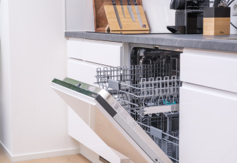 Moderne Glampingküche mit offener Einbau-Geschirrspülmaschine, bereit für Geschirr und Besteck.