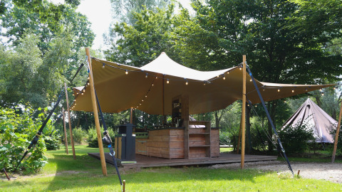 Le lodge Glamptent GT au Holiday Park BreeBronne, Pays-Bas, avec terrasse en bois et guirlandes lumineuses.