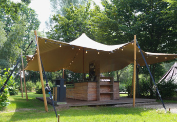 Le lodge Glamptent GT au Holiday Park BreeBronne, Pays-Bas, avec terrasse en bois et guirlandes lumineuses.