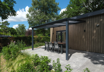 Terrasse moderne couverte avec table à manger au Loevestein Deluxe, Veluwepark de Bosgraaf, aux Pays-Bas.