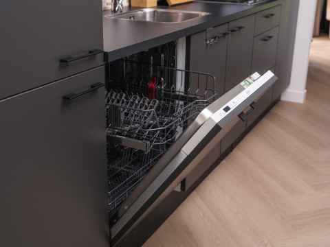 Opvaskemaskine integreret i et moderne køkken ved et lodge, med døren åben og tomme kurve synlige.