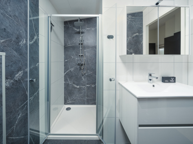 Baño moderno en un lodge con ducha de vidrio, paredes de mármol y lavabo elegante con gran espejo