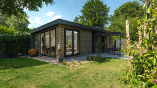 Lodge moderne Zypendaal avec grandes baies vitrées, terrasse et jardin, entouré de verdure et d’arbres.