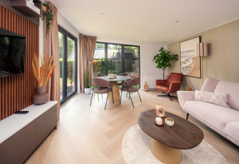 Helles, modernes Wohnzimmer in der Lodge Zypendaal im Veluwepark de Bosgraaf, Niederlande, mit Panoramafenstern.
