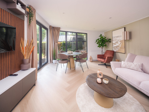 Helles, modernes Wohnzimmer in der Lodge Zypendaal im Veluwepark de Bosgraaf, Niederlande, mit Panoramafenstern.
