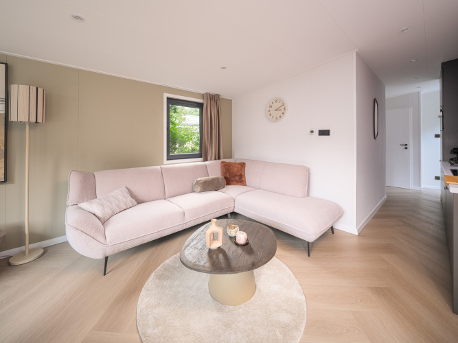 Sala de estar moderna de lodge en Zypendaal, Veluwepark de Bosgraaf, Países Bajos, con elegante decoración clara.