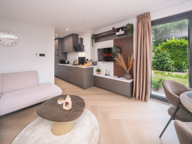 Moderna cabaña Zypendaal en Veluwepark de Bosgraaf, Países Bajos, con salón luminoso y vistas al jardín.