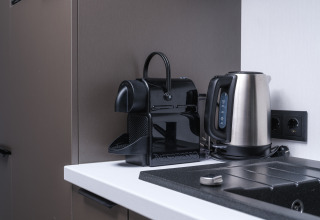 Moderne Nespresso-Kaffeemaschine und Edelstahl-Wasserkocher in der Küche der Zypendaal-Lodge im Veluwepark de Bosgraaf.