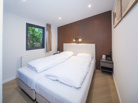Schlafzimmer in der Lodge Zypendaal im Veluwepark de Bosgraaf, Niederlande, mit Doppelbett und modernem Design.