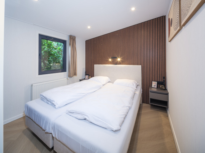 Dormitorio de la cabaña Zypendaal en Veluwepark de Bosgraaf, Países Bajos, con cama doble y decoración moderna.