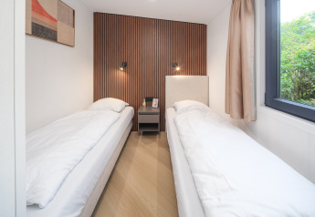 Habitación moderna con dos camas individuales, paredes de madera en Zypendaal Lodge, Veluwepark de Bosgraaf.