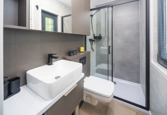 Bagno moderno al lodge Zypendaal di Veluwepark de Bosgraaf con doccia in vetro, lavabo e servizi.