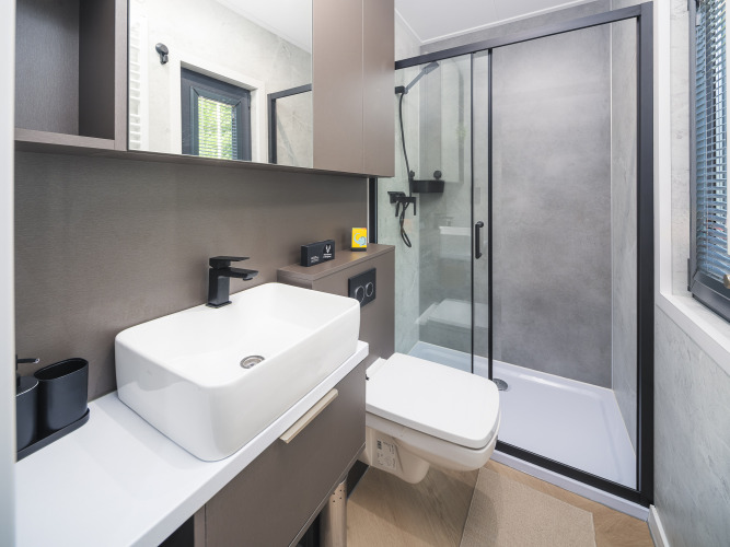 Baño moderno en la cabaña Zypendaal, Veluwepark de Bosgraaf, con ducha de vidrio, lavabo y aseo.