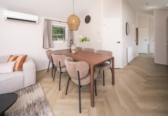 Sala da pranzo moderna in un lodge con tavolo in legno, sei sedie imbottite e pavimento in legno chiaro.