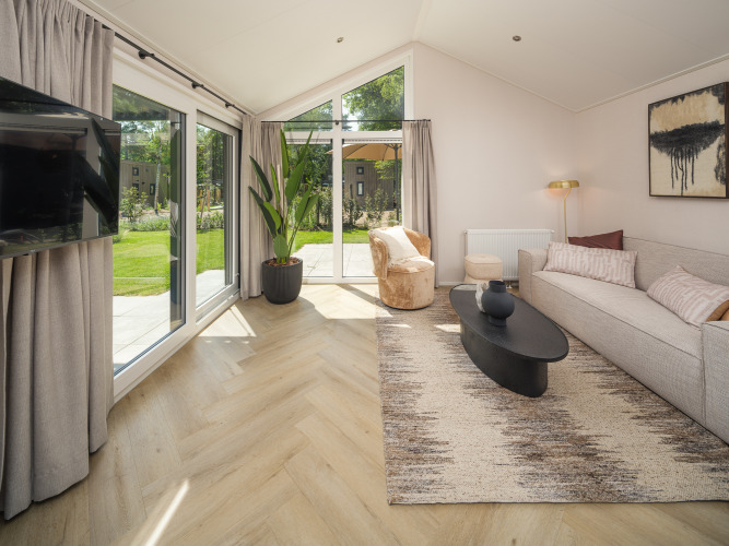 Helles Lodge-Wohnzimmer mit großen Fenstern, moderner Einrichtung und Blick auf den Garten.