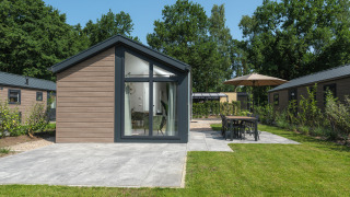 Moderne Doornenburg Lodge met houten gevel, grote ramen, terras en groene tuin op het erf.