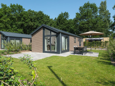 Buitenaanzicht van Doornenburg Lodge op Veluwepark de Bosgraaf in Nederland met terras en tuin.