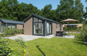 Vue extérieure de la Doornenburg Lodge à Veluwepark de Bosgraaf, Pays-Bas, avec terrasse et jardin.