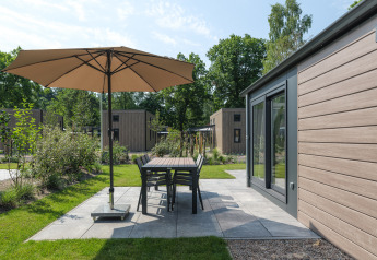 Patio esterno al Doornenburg Lodge nel Veluwepark de Bosgraaf, Paesi Bassi, con ombrellone e arredi da giardino.