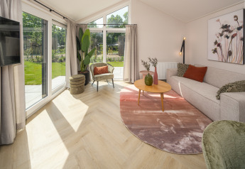 Salon lumineux à Doornenburg Lodge Comfort, Veluwepark de Bosgraaf, Pays-Bas, avec grandes fenêtres sur le jardin.