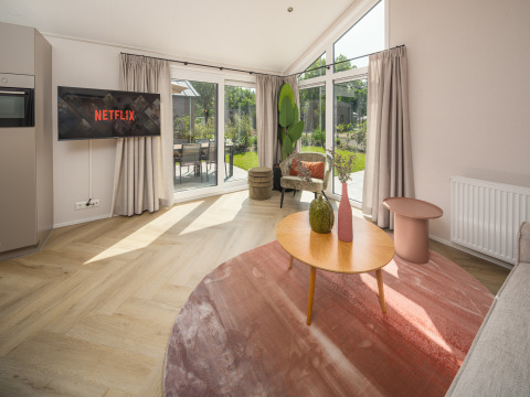 Salon de Doornenburg Lodge Comfort, Veluwepark de Bosgraaf, décor moderne et grandes baies vitrées.
