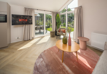 Living room at Doornenburg Lodge Comfort, Veluwepark de Bosgraaf, with modern décor and large windows.