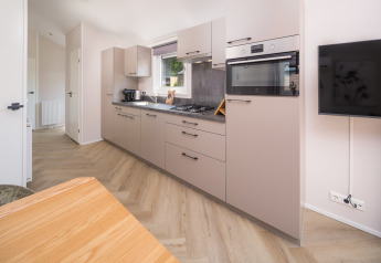 Cocina moderna en Doornenburg Lodge Comfort en Veluwepark de Bosgraaf, Países Bajos, con muebles beige elegantes.