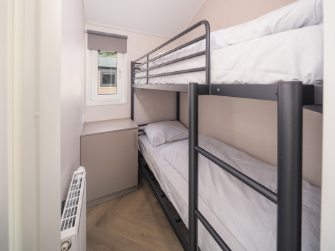 Petite chambre avec lits superposés en métal et fenêtre à Doornenburg Lodge Comfort, Veluwepark de Bosgraaf.