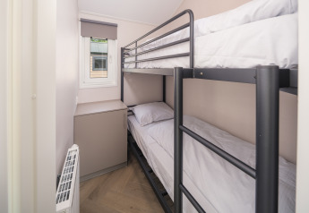 Petite chambre avec lits superposés en métal et fenêtre à Doornenburg Lodge Comfort, Veluwepark de Bosgraaf.