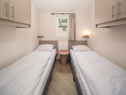 Chambre avec deux lits simples, draps blancs et placards à Doornenburg Lodge Comfort, Veluwepark de Bosgraaf.
