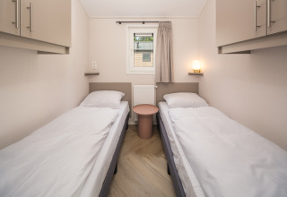 Kamer met twee eenpersoonsbedden, witte lakens en kasten in Doornenburg Lodge Comfort, Veluwepark de Bosgraaf.