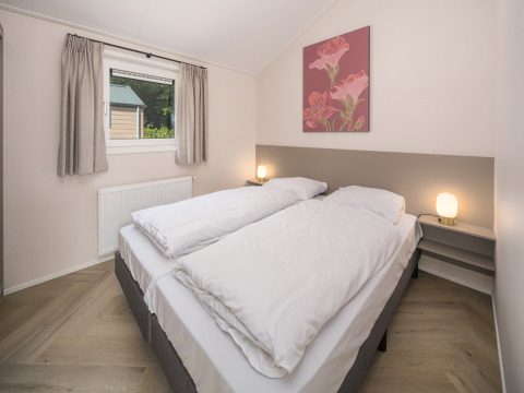 Chambre à Doornenburg Lodge Comfort au Veluwepark de Bosgraaf, avec deux lits et ambiance lumineuse douce.