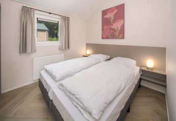 Dormitorio de Doornenburg Lodge Comfort en Veluwepark de Bosgraaf, Países Bajos, con dos camas y lámparas.