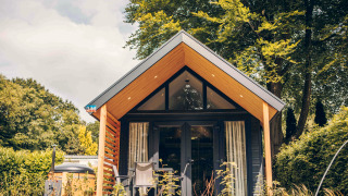 Tiny house Tiny Loft avec bain à remous, façade bois moderne, terrasse et arbres verdoyants autour.