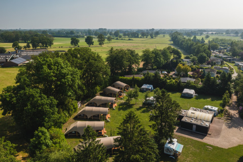 Vista aérea del Holiday Resort 't Schuttenbelt en Overijssel, Países Bajos, con tiendas y caravanas rodeadas de verde.