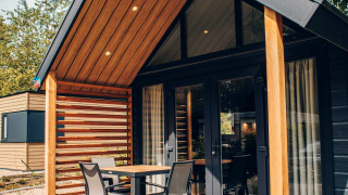 Tiny house moderne avec bardage bois, terrasse couverte, mobilier de jardin et environnement naturel.