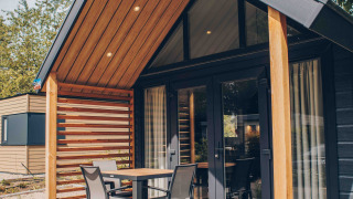 Tiny house moderne avec bardage bois, terrasse couverte, mobilier de jardin et environnement naturel.