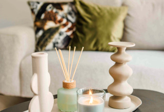 Table basse décorée dans une tiny house avec bougie allumée, diffuseur de parfum et vases décoratifs.