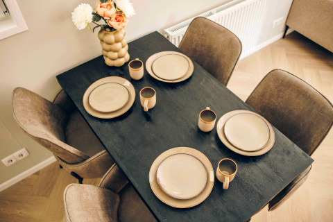 Dining table with four place settings and a flower vase in a Tiny Loft at Veluwepark de Bosgraaf, Netherlands.